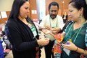 Jasmine Bostock, Leonard Imbiri and Sarah Eagle Heart helping each other tie a prayer string for unity during Indigenous Peoples Pre-Assembly.